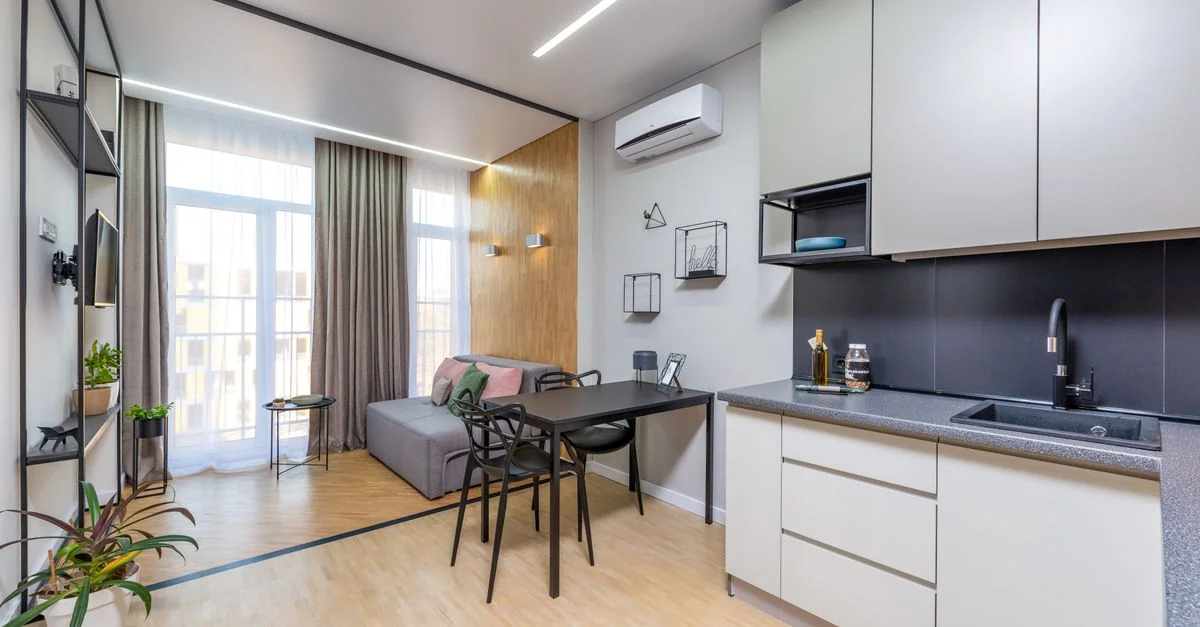 Un appartement studio élégant et contemporain avec des meubles épurés et des appareils de cuisine modernes.