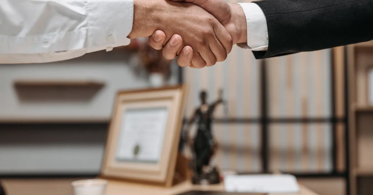 Gros plan sur une poignée de main entre deux professionnels dans un cadre de bureau moderne, mettant en avant le partenariat et l'accord.