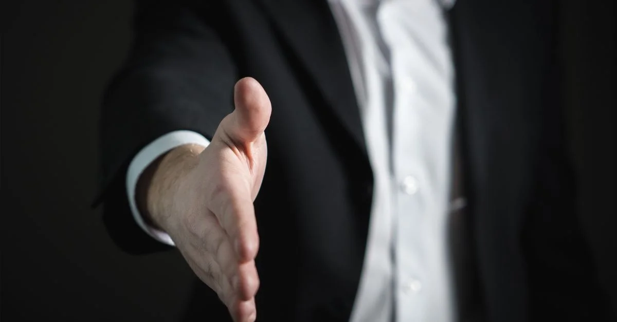 Gros plan d'un homme d'affaires tendant la main pour une poignée de main, symbolisant l'accord et le partenariat.